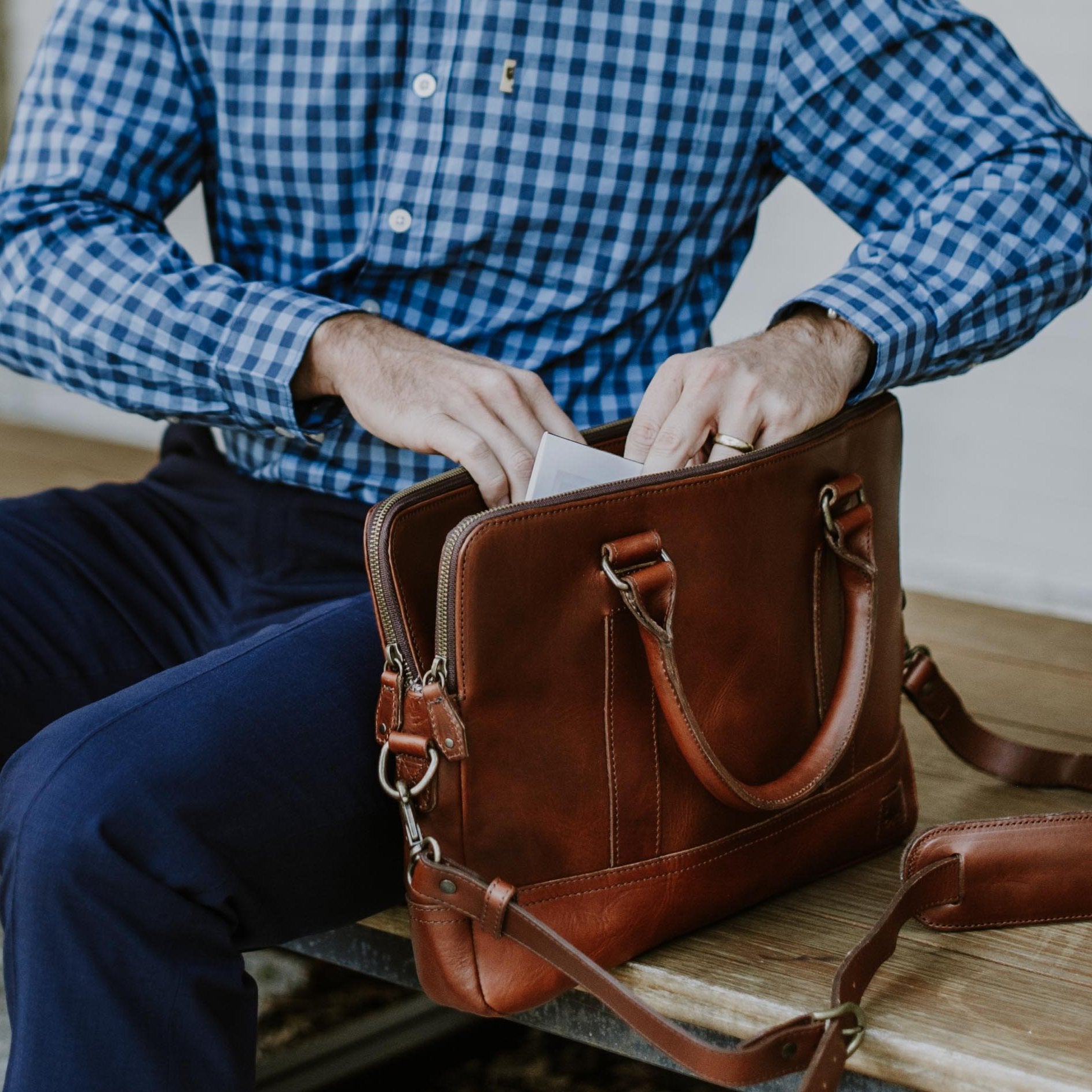 Stylish man accessing contents of a sophisticated leather attache bag. Men's Best Leather Attache | Elderwood hover